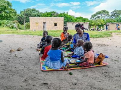 A mother giving food to her children in a PD Hearth session