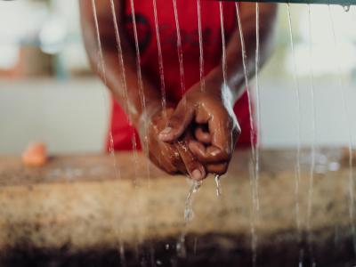 A child is washing her hands at a handwashing station.