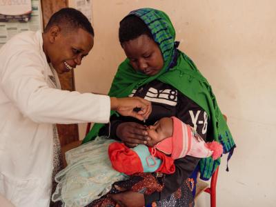 A medical worker immunises a child health by its mother 