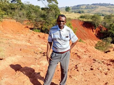 Mr. Dlamini standing next to a donga that is threatning livelihoods in his community.