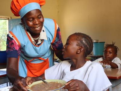A cook giving school meals to children at school