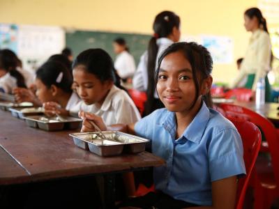 A girl eats a school meal in Cambodia