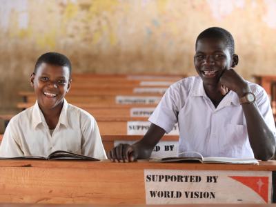 Lengai and Nesi, students at Olbokishu Primary School in Oljoro No. 5, pose in their newly furnished, colorful classroom during an interview with World Vision Tanzania’s Mobile Journalist, Alpha Nsemwa.