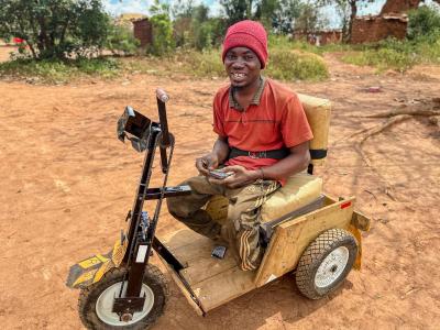 Aimé in his wheelchair received from World Vision
