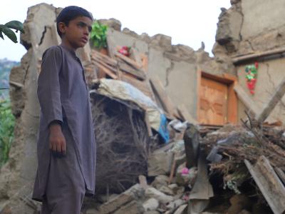 A boy stands in front of a building destroyed by the earthquake