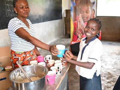 Jenovie, 12 years old, beams with joy as she enjoys her porridge. DRC/Didier Nagifi/ 2025.