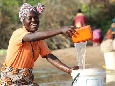 Sugineta draws water from the riverbed using traditional methods.