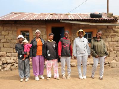 Maletsepileng and her daughters standing together in their new winter clothes, smiling and enjoying warmth and comfort.