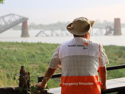 World Vision emergency response staff looking out over water towards a bridge in the distance.