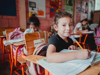 little girl writing in her notebook in the classroom