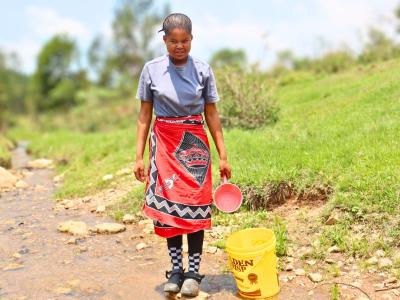 Sibonelo standing on a rock on the river she used to get water from before World Vision brougt water to her community. 
