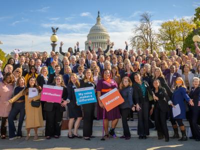 People gather on steps in front of the U.S. Capitol building holding signs saying "Advocate" and "My voice makes a difference"