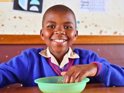A learner enjoying a school meal inside a classroom.