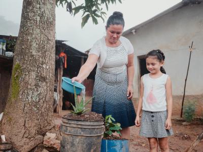 A woman and a young child water small plants outside their home in a rural Honduran village.