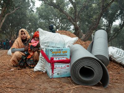 A mother and her child receive winterization kits in Mahottari