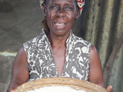 Salfina holds a sieve filled with rice.