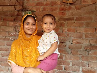 A beaming Sumi holds her young son, Jabelenu, close at their home, embodying the health and hope fostered by the PD/Hearth nutrition program.