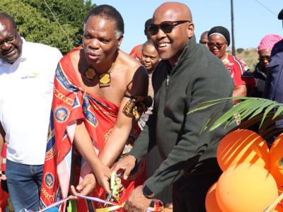 Two people cutting a ribbon.