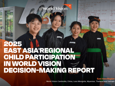 Four children stand together in a classroom wearing traditional clothing, with educational posters and handwritten charts displayed on the walls behind them. The image appears on the cover of the 2025 East Asia Regional Child Participation in World Vision Decision-Making Report.