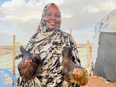 Fatima proudly displaying two of the chickens she  received through the project