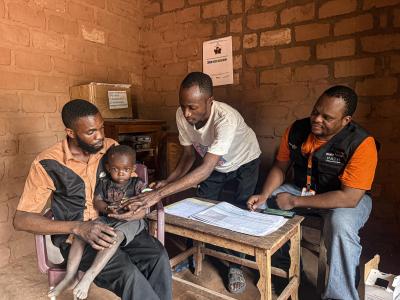 community health worker in a care site taking measures of a child