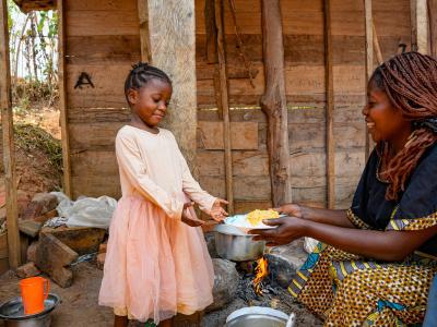 Maliyetu serving food to one of her children