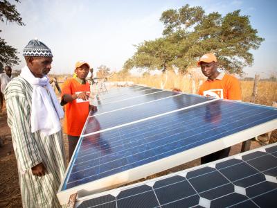 World Vision staff and a village chief inspect solar panels for a water pump in Senegal.