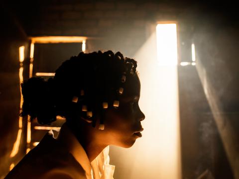 A girl sits in her home with the sun coming in in the background