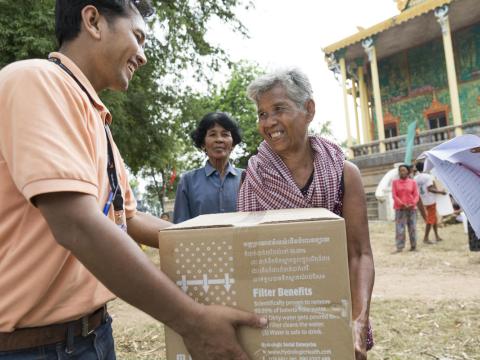 World Vision staff hands community member water filter during flooding event