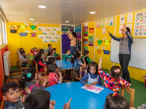 Syrian refugee children leaning how to count with the help of their teachers