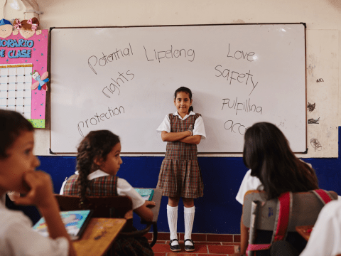 Girl standing in the middle of classroom with her arms crossed