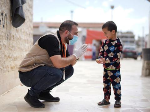 World Vision staff kneeling with young boy