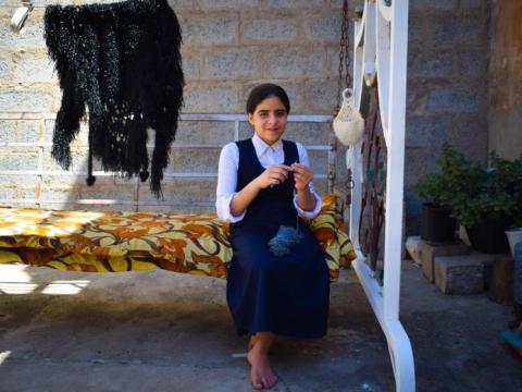 Mays knitting on the swing in the yard of her home