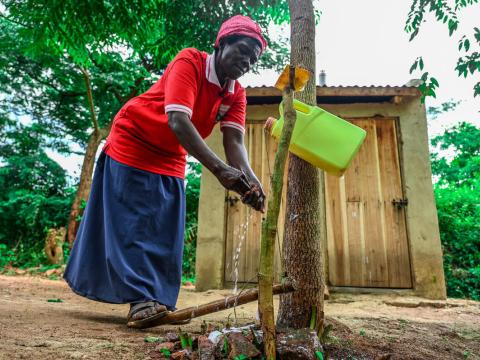 Woman washing hands after visiting pit latrine