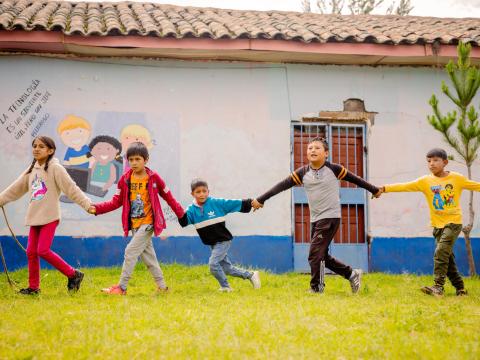 Children holding hands while walking in a line. 