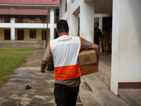 WVI Staff carries a box in distribution center 
