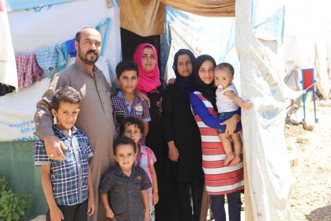 A Syrian family outside their refugee shelter