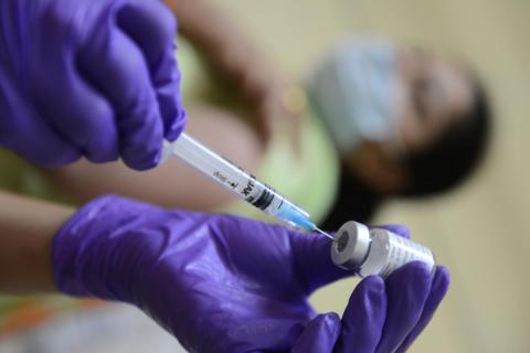 Vaccine being administered by a health professional wearing purple gloves