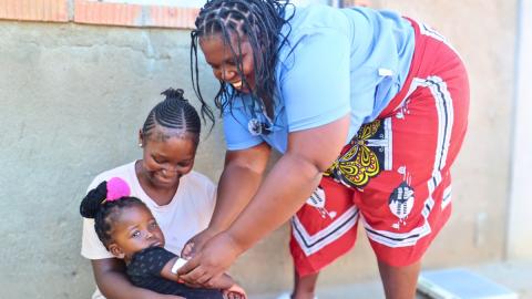 Fakazile, a rural health motivator conducting growth monitoring on a 2-year-old child. 
