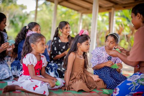 A group of young girls sit outside during a children's club