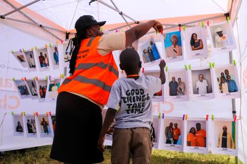 A child receives assistance while taking down a photograph of the sponsor he chose.