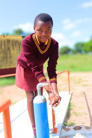A learner washing hands after using the toilet in her school. 