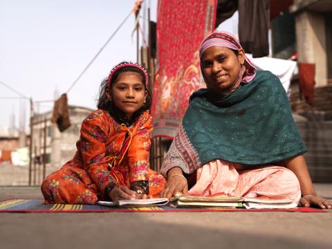 Jannat, a young heart surgery survivor, smiling happily while studying with her mother at home.