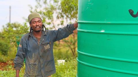 A man standing next to a water tank. 