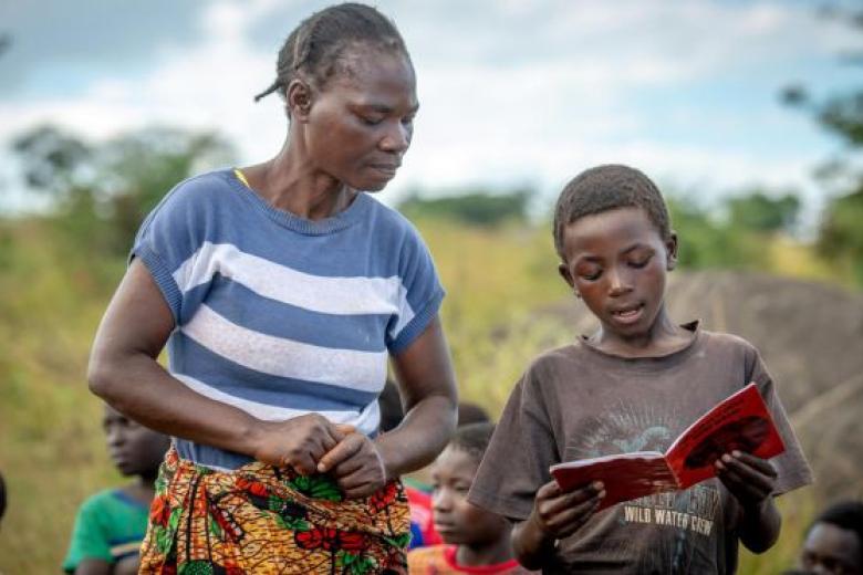 Featured Image: Community reading club volunteer, Jenara Mumbulu, listens to and helps Lightwell, 10, with his reading at a World Vision's reading camp in Zambia. (Photo credit: Laura Reinhardt / World Vision).