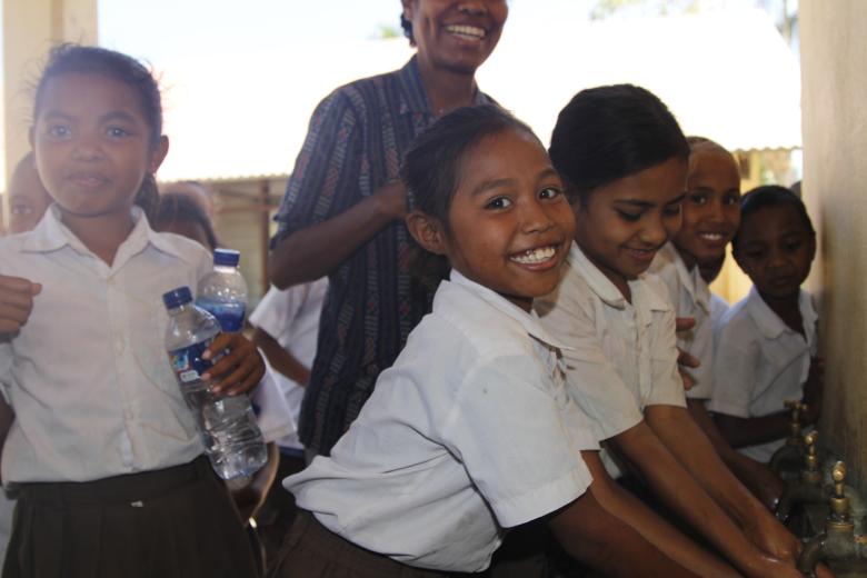 Nine-year-old Nensia happily washes her hands with clean water at her school. Photo: Jaime dos Reis/World Vision