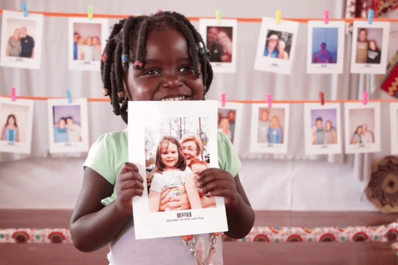 A child holds the picture of the sponsor they chose.