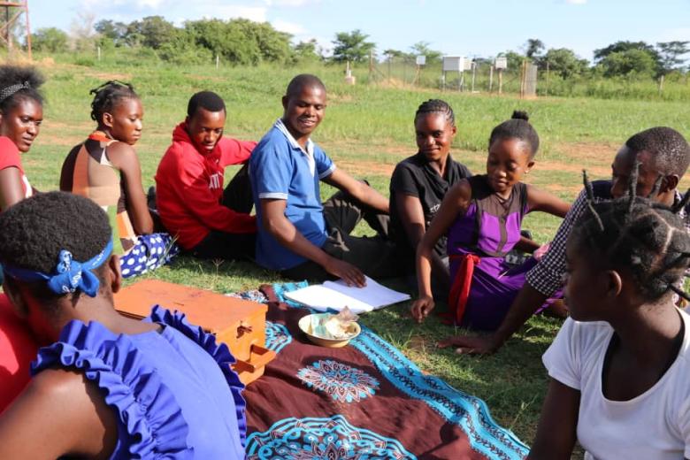 Young people sit around a bowl of savings