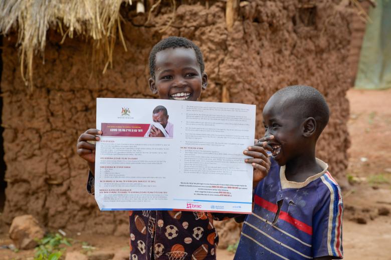 Children in Bidibidi holding a COVID-19 Poster