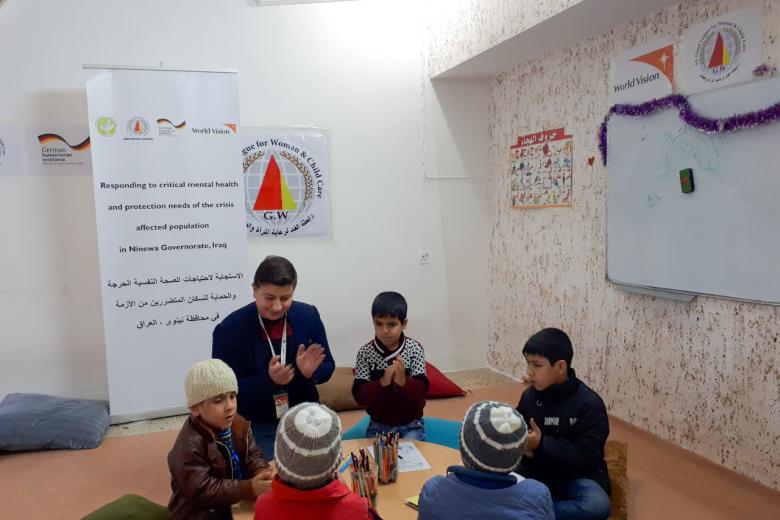 Adil (in the brown jacket to the left of facilitator Muath) participating in group activities in the Child Friendly Space